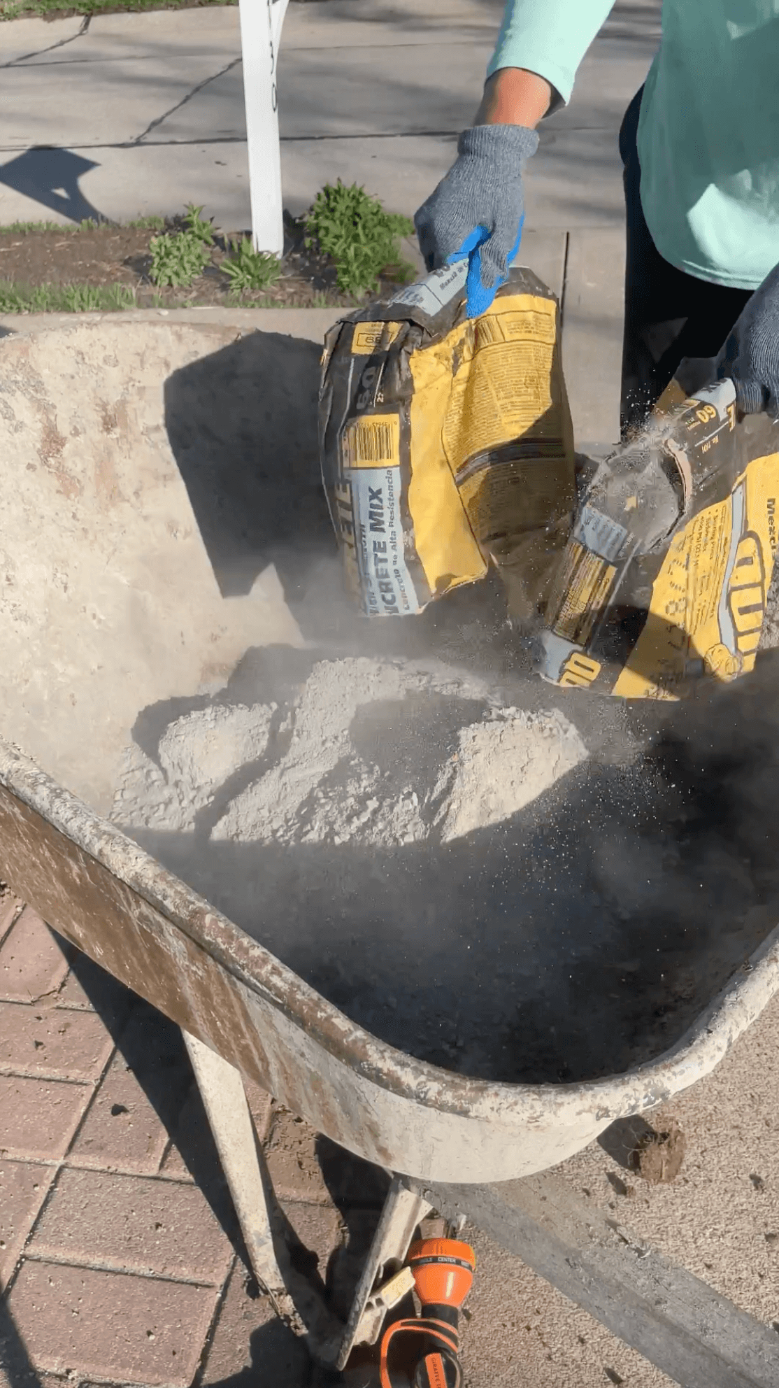 Pouring a bag of concrete into a wheel barrow. 